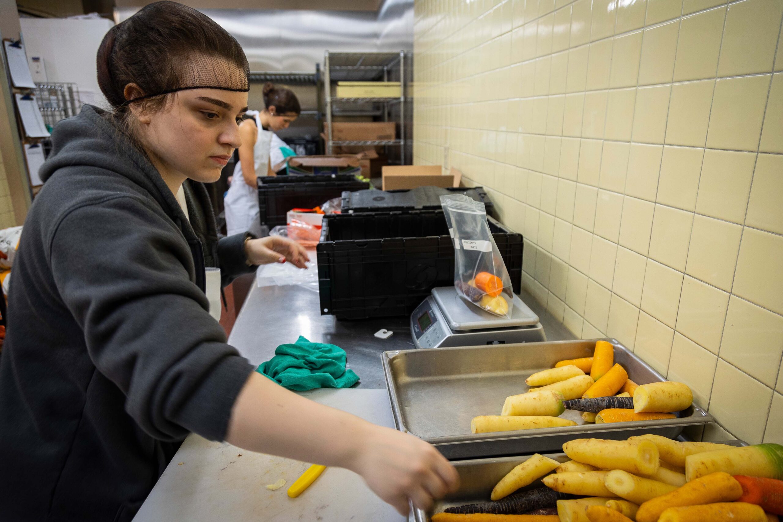 Tamara Altrarac, Cognitive Science major student, prepares carrots for a meal kit